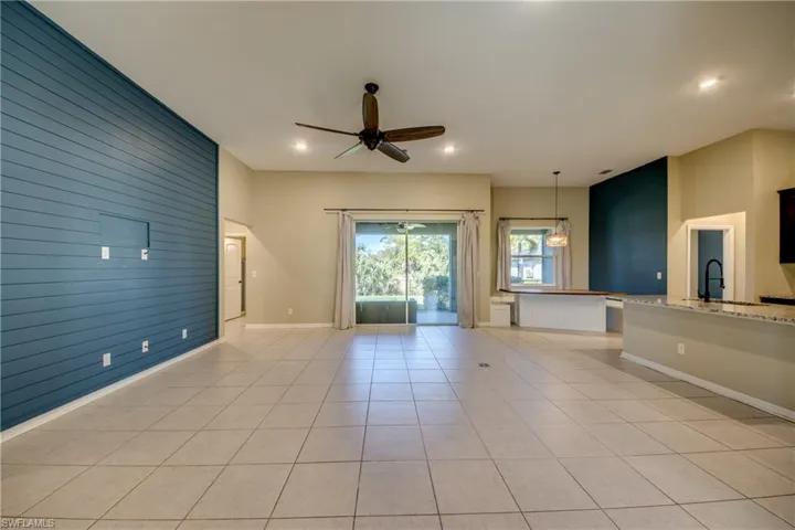 Unfurnished living room featuring wooden walls, ceiling fan, an accent wall, light tile patterned floors, and recessed lighting
