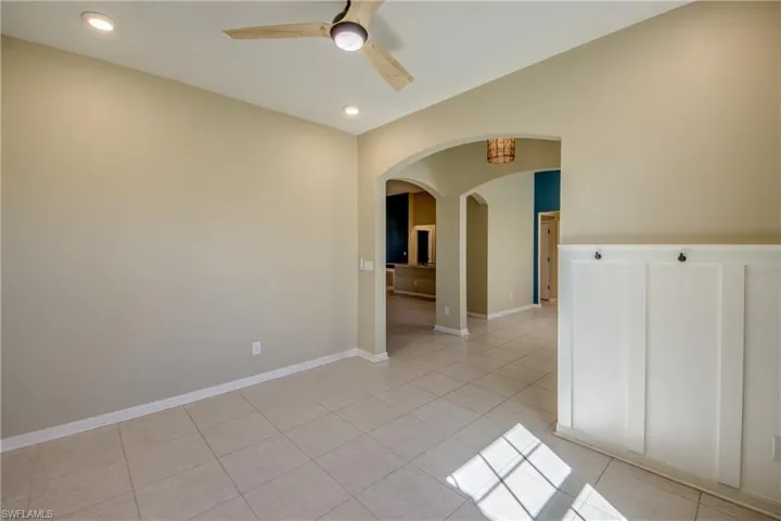 Spare room with arched walkways, a ceiling fan, light tile patterned flooring, and recessed lighting