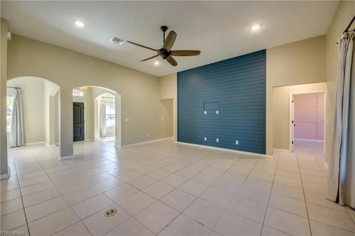 Spare room with a ceiling fan, light tile patterned flooring, arched walkways, a high ceiling, and recessed lighting