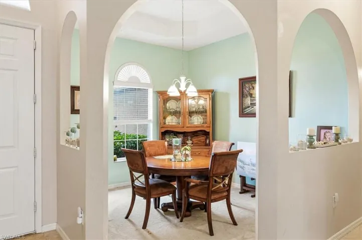 Open-concept dining area featuring architectural archways, built-in wall niches, and a large window with an arched transom