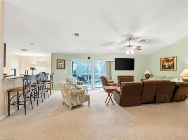 Virtually Staged Open-concept living space featuring vaulted ceilings, light-toned carpeting, and a glass sliding door to the exterior