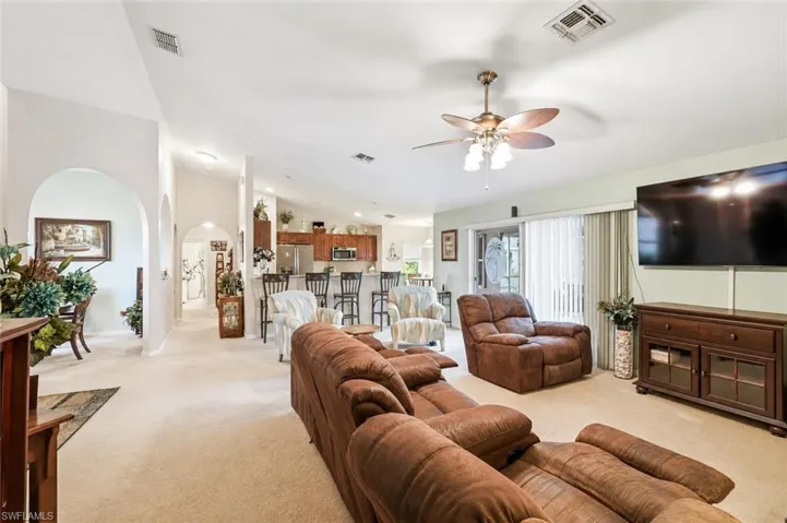 Virtually Staged Living area with vaulted ceiling and ceiling fan, featuring carpet flooring and sliding glass doors