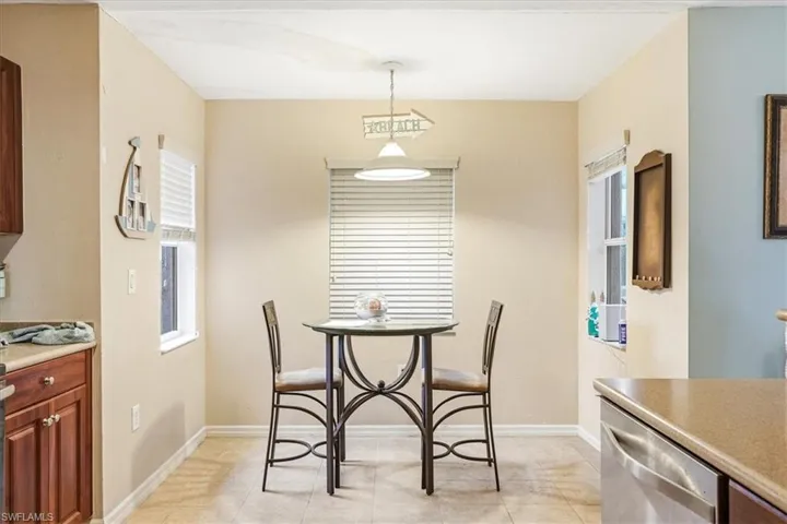 Dining area featuring tiled flooring, a suspended ceiling light fixture, and two windows with blinds
