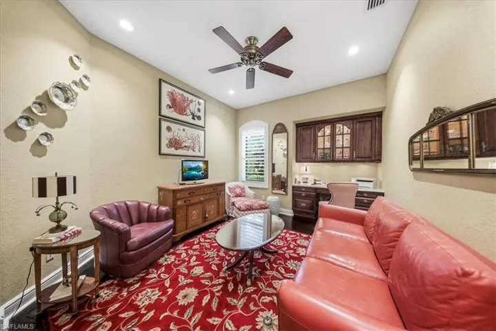 Living room with a textured wall, built in study area, baseboard heating, ceiling fan, and recessed lighting