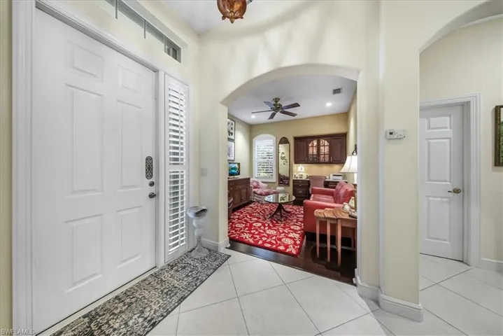 Foyer entrance featuring arched walkways, light tile patterned flooring, and a ceiling fan