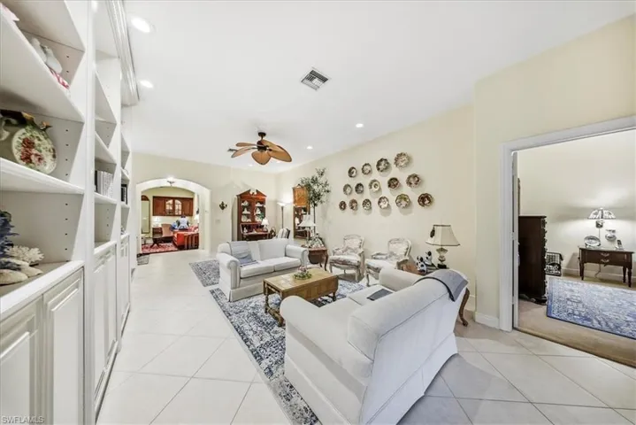 Living area with arched walkways, light tile patterned floors, ceiling fan, and recessed lighting