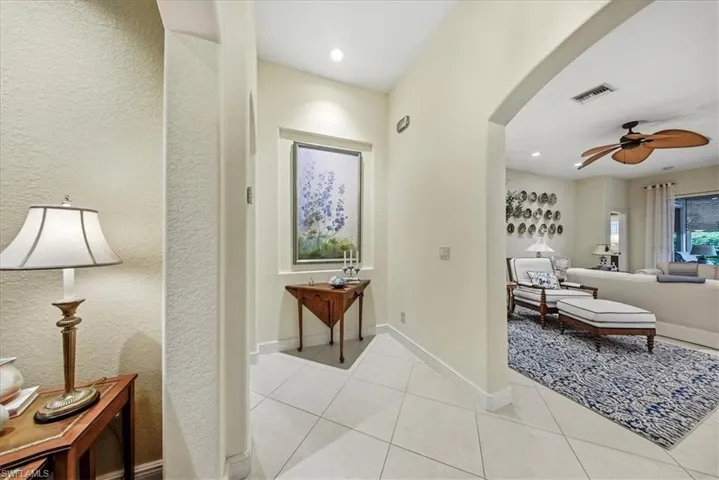 Hall featuring arched walkways, light tile patterned floors, and a textured wall