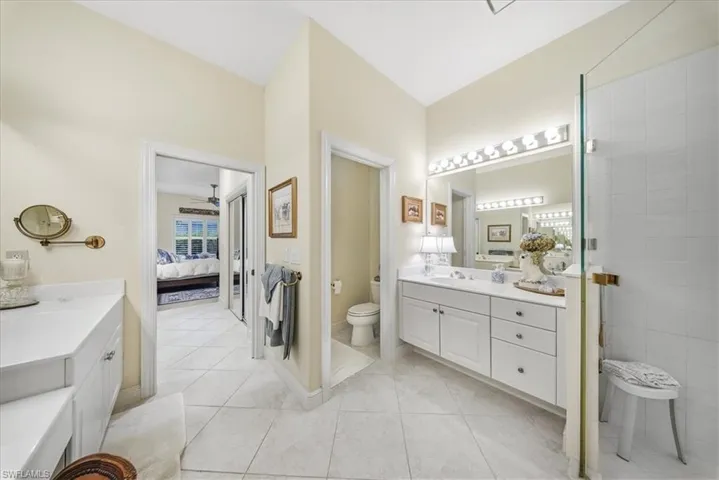Full bathroom featuring ensuite bath, two vanities, and light tile patterned floors