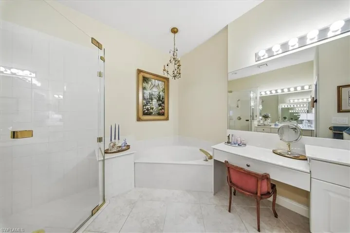 Bathroom featuring a stall shower, a garden tub, vanity, a chandelier, and light tile patterned floors