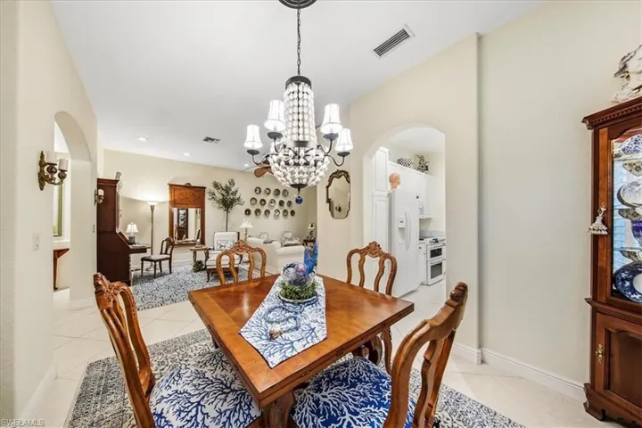 Dining room with arched walkways, light tile patterned floors, a chandelier, and recessed lighting