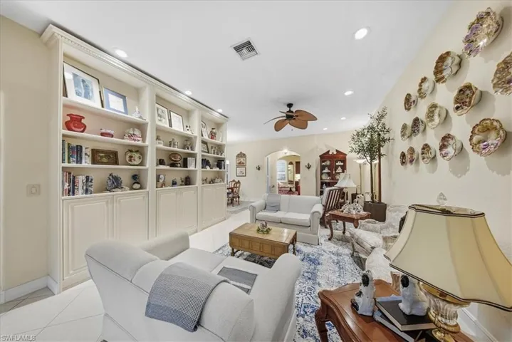 Living room with arched walkways, tile patterned flooring, ceiling fan, and recessed lighting