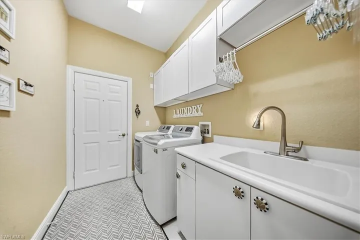 Laundry room featuring cabinet space, washing machine and dryer, and light tile patterned floors