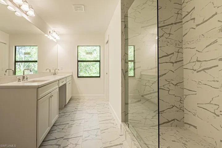 Bathroom featuring tiled shower and vanity