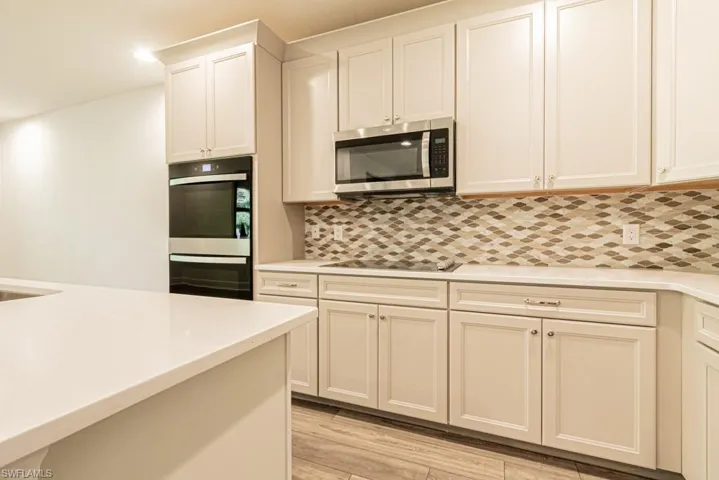 Kitchen featuring decorative backsplash, appliances with stainless steel finishes, and light wood-type flooring