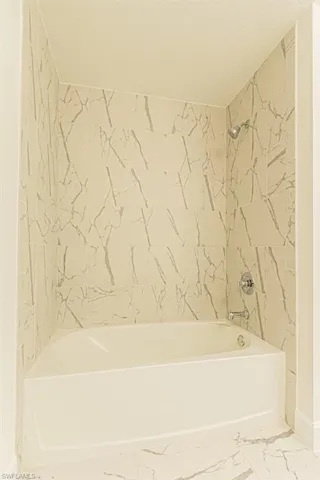 Bathroom featuring a textured ceiling and tiled shower / bath