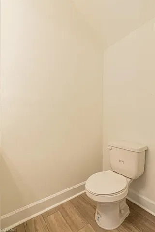 Bathroom featuring toilet, lofted ceiling, and hardwood / wood-style flooring