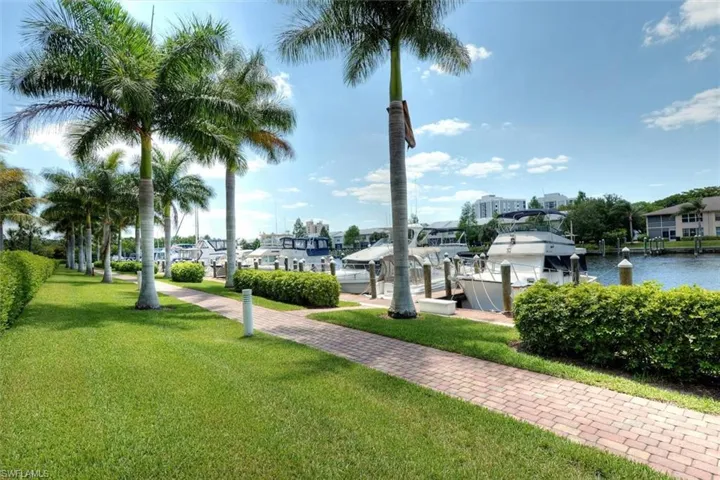 Surrounding community featuring a yard, a water view, a boat dock, and boat lift