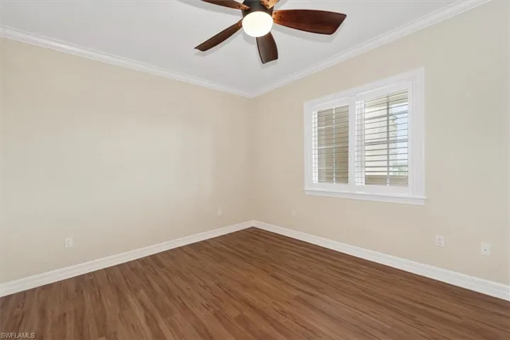3rd bedroom room featuring ornamental molding, dark wood-style flooring, and ceiling fan