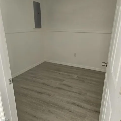 Empty room with wood finished floors, electric panel, and baseboards