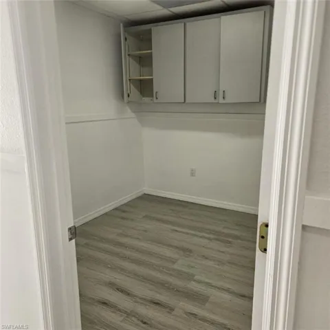 Unfurnished room featuring a drop ceiling, baseboards, and wood finished floors