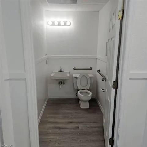 Bathroom featuring wood finished floors, toilet, a sink, and a paneled ceiling