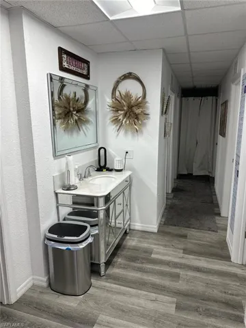 Hall with a sink, baseboards, a drop ceiling, wood finished floors, and a textured wall