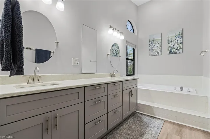 Bathroom featuring tiled tub, vanity, and hardwood / wood-style flooring