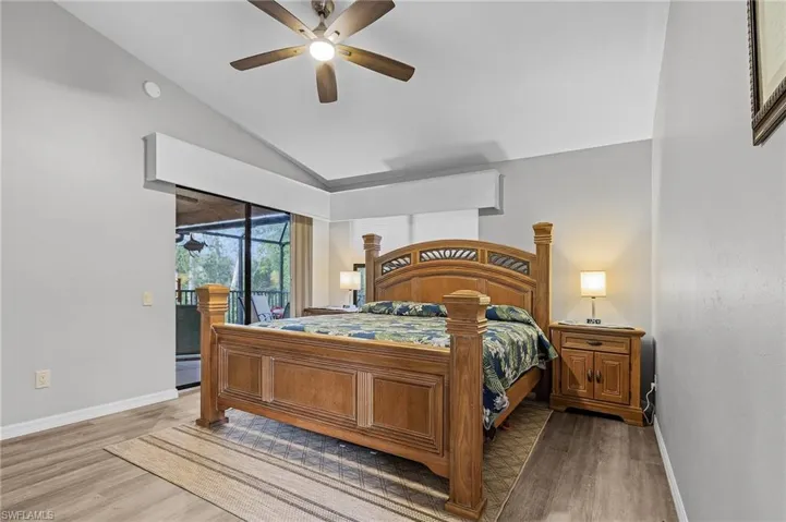 Bedroom featuring access to exterior, ceiling fan, wood-type flooring, and vaulted ceiling