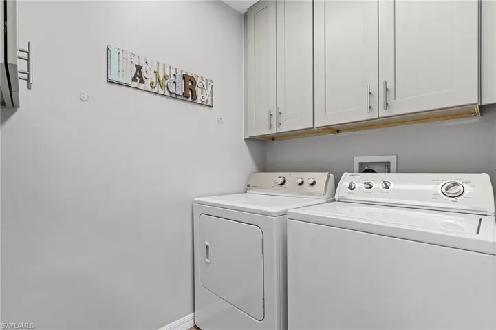 Laundry area with washer and clothes dryer and cabinets