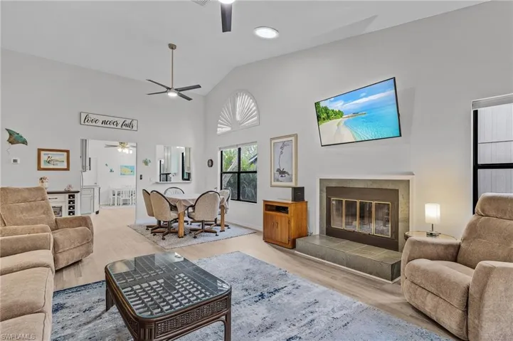 Living room featuring a fireplace, high vaulted ceiling, and light wood-type flooring