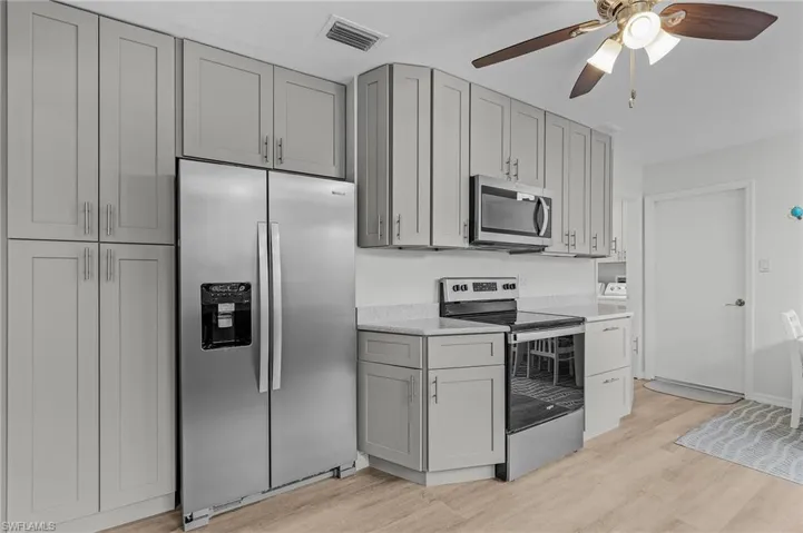 Kitchen featuring light wood-type flooring, stainless steel appliances, gray cabinets, and ceiling fan