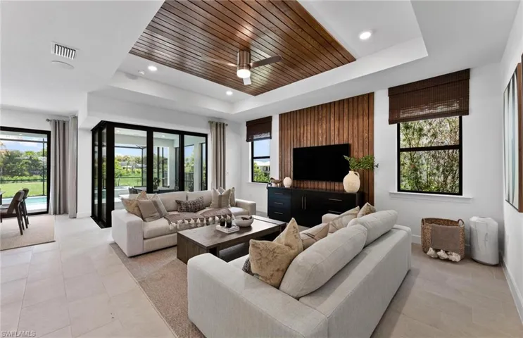 Living room featuring a wood tray ceiling, a ceiling fan, and recessed lighting