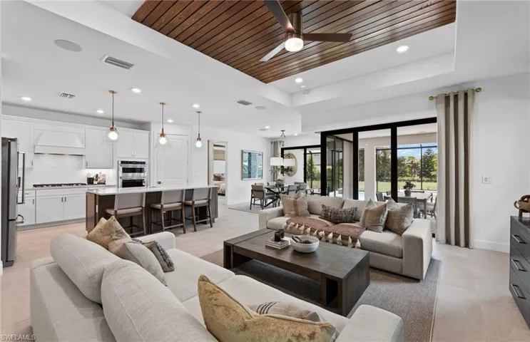 Living room with a wood tray ceiling, plenty of natural light, ceiling fan, and recessed lighting