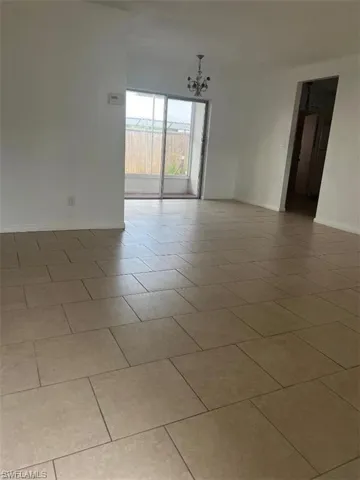Empty room with light tile patterned floors and an inviting chandelier