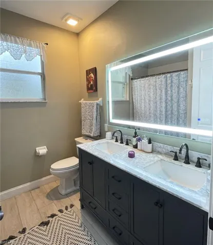 Bathroom with double vanity, a shower with shower curtain, and wood tiled floors