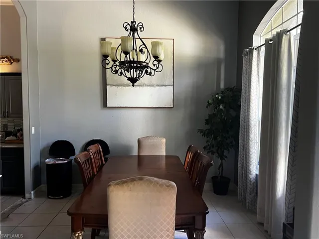 Dining room featuring light tile patterned flooring, arched walkways, and a chandelier