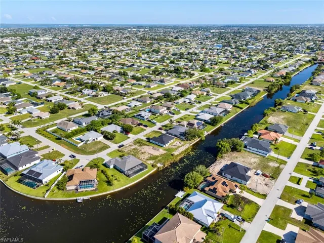 Aerial view of property and surrounding area with a nearby body of water and nearby suburban area