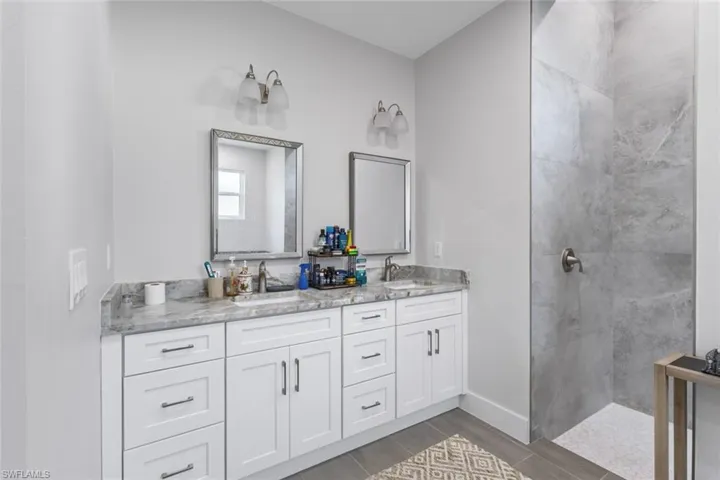 Full bath featuring double vanity, walk in shower, and wood finished floors