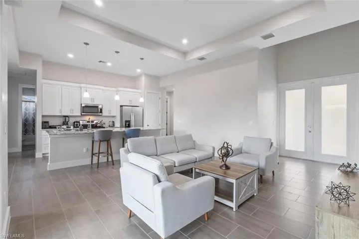 Living area featuring a raised ceiling, recessed lighting, french doors, and light tile patterned flooring