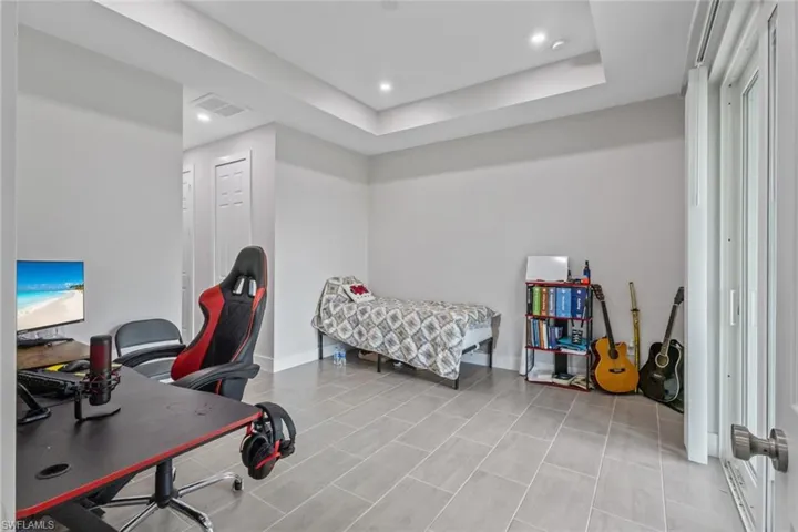 Bedroom with a desk, a raised ceiling, and recessed lighting