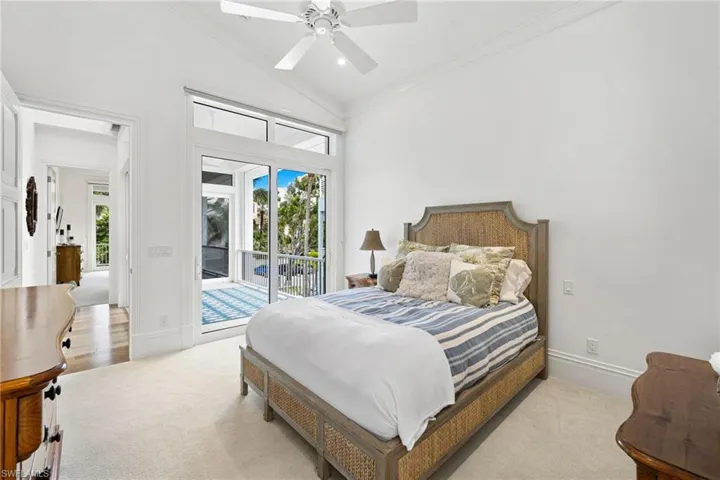 Bedroom featuring ornamental molding, lofted ceiling, access to outside, multiple windows, and a ceiling fan