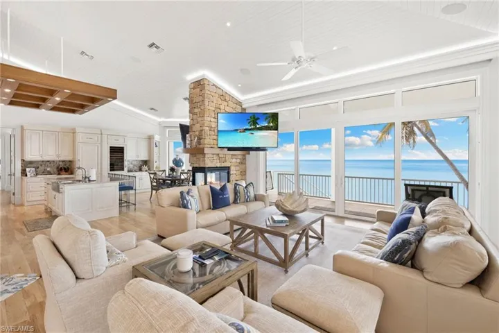 Living room with light wood-style floors, a stone fireplace, ceiling fan, wood ceiling, and recessed lighting