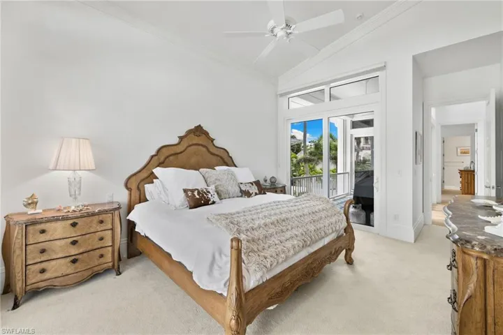 Bedroom with crown molding, vaulted ceiling, light colored carpet, access to exterior, and ceiling fan