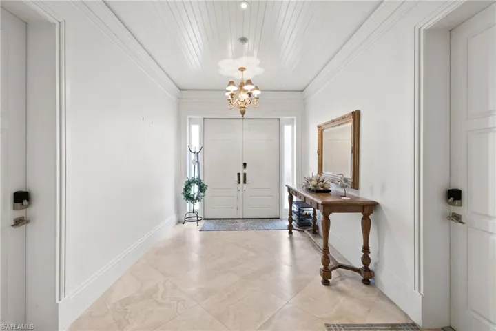 Foyer entrance featuring a chandelier, ornamental molding, and light tile patterned floors