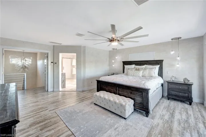 Bedroom featuring ceiling fan with notable chandelier and light wood-type flooring