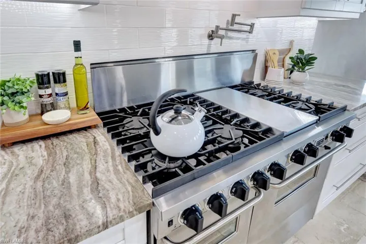 Details with white cabinetry, stainless steel range, and light stone countertops