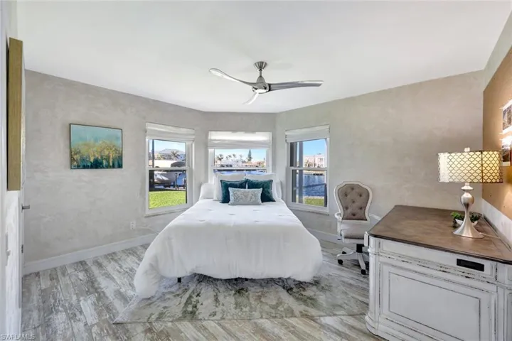 Bedroom with ceiling fan, light hardwood / wood-style floors, and multiple windows
