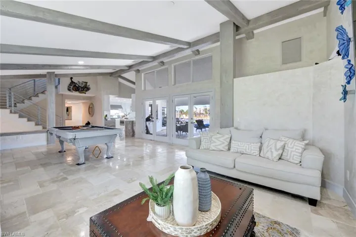 Living room with high vaulted ceiling, beam ceiling, billiards, and french doors