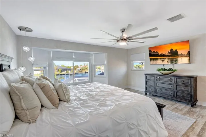 Bedroom with access to outside, ceiling fan, a water view, and light wood-type flooring