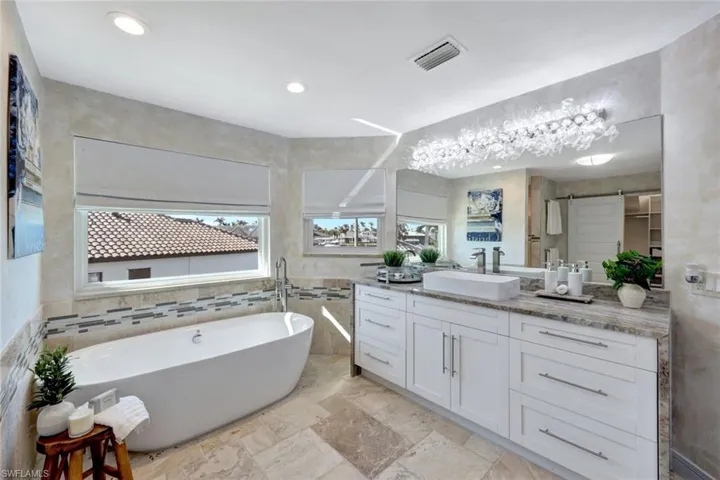 Bathroom featuring a bath, vanity, and tile walls